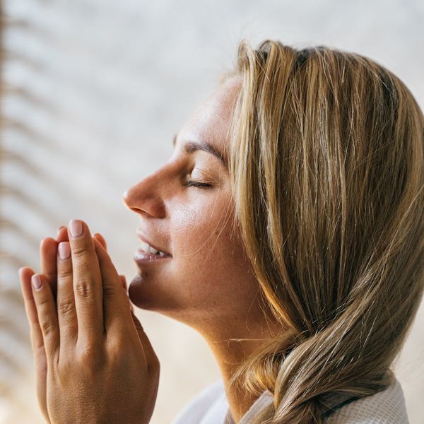 Woman meditating with a calm expression, surrounded by soft light.